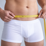 alargar el pene adelgazando. Hombre midiendo la cintura para ilustrar cómo adelgazar puede reducir la grasa púbica y hacer más visible el pene