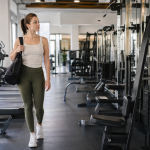 Mujer recorriendo un gimnasio moderno antes de elegir dónde entrenar
