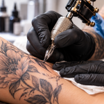 Artista realizando un tatuaje con máquina sobre la piel en un estudio profesional